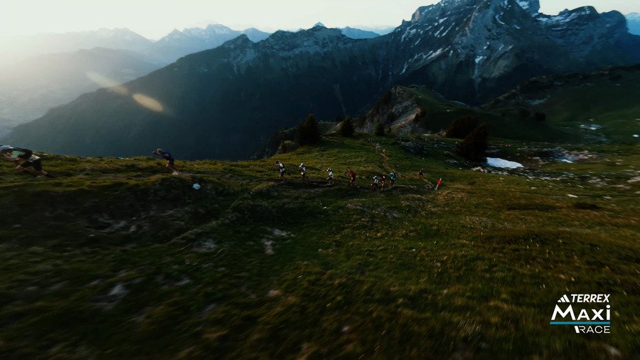 Runners on a high trail at sunrise, mountains behind