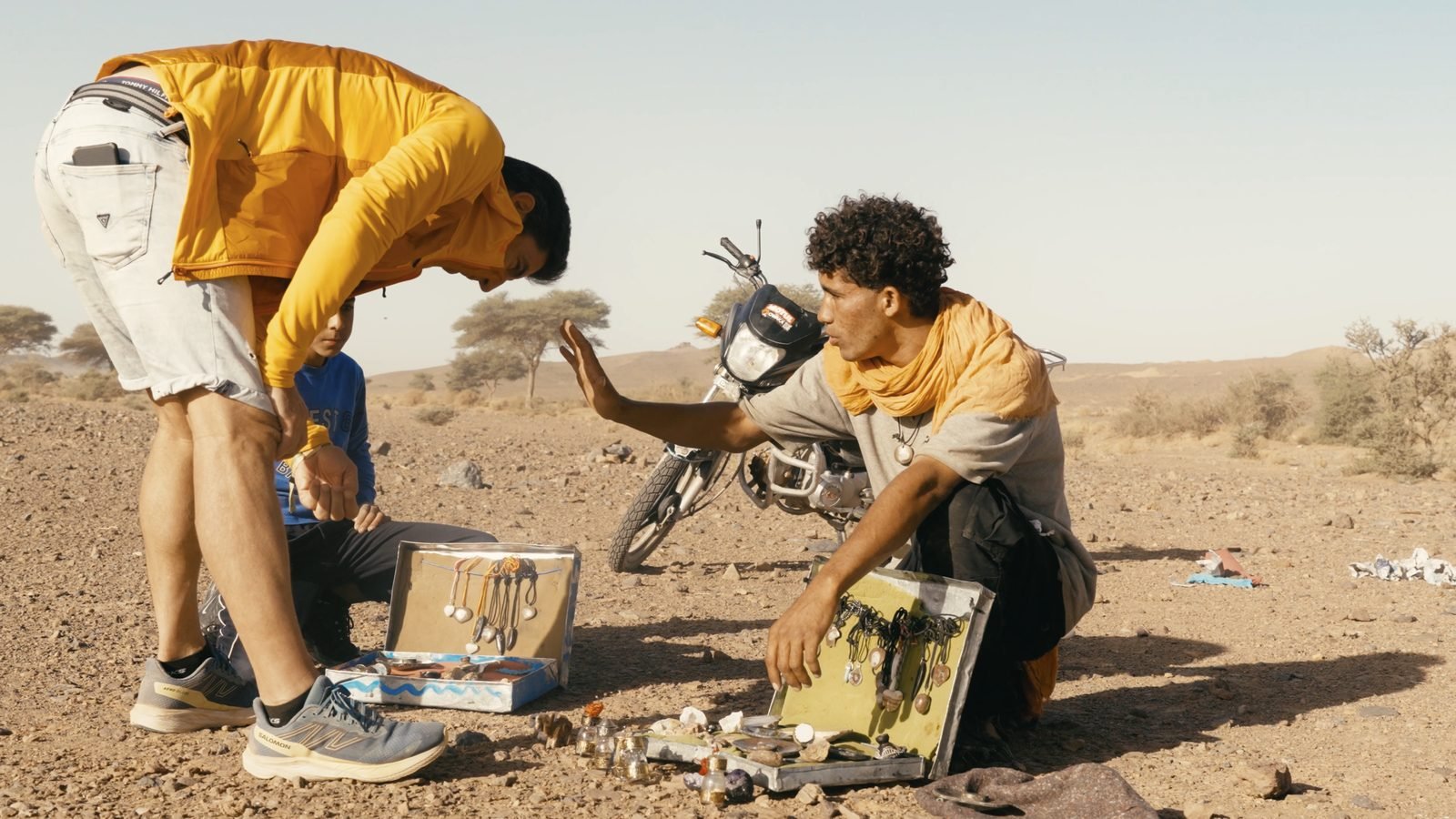 Clément and Paul at the bivouac, sorting gear beside the bike, Rallye du Maroc 2025